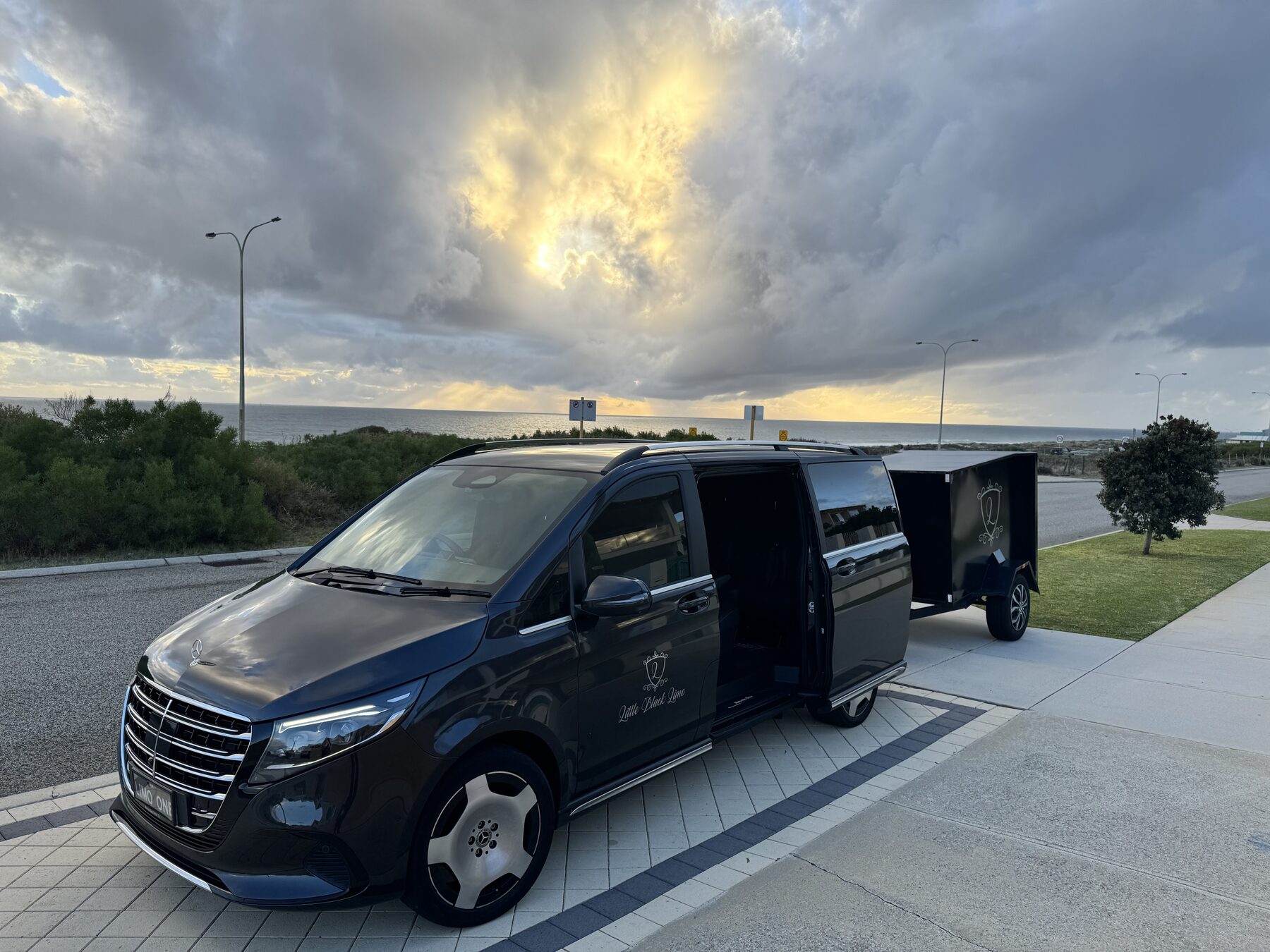 Limo van with trailer by the coast at sunset